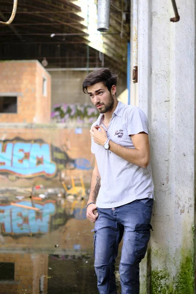 Dejenere olmuş terk edilmiş fabrikadaki yakışıklı siyah saçlı İtalyan adam. Yüksek kalite fotoğraf