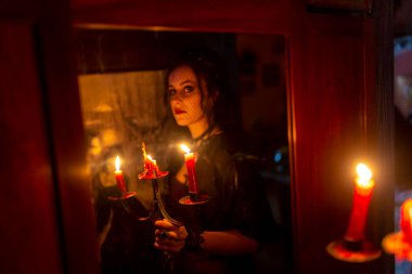 Kanlı dişleri olan güzel esmer vampir kız elinde mumla kalenin etrafında dolaşıyor. Yüksek kalite fotoğraf