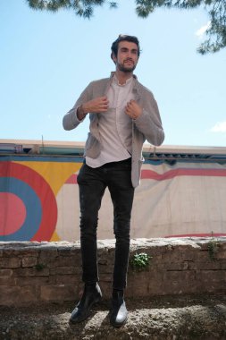 Yakışıklı, siyah saçlı İtalyan çocuk alçak duvarda yürüyor. Yüksek kalite fotoğraf