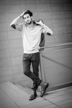 Yakışıklı, siyah saçlı, metal korkuluklara yaslanmış bir çocuk. Yüksek kalite fotoğraf