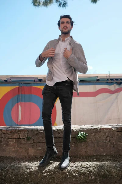 Yakışıklı, siyah saçlı İtalyan çocuk alçak duvarda yürüyor. Yüksek kalite fotoğraf