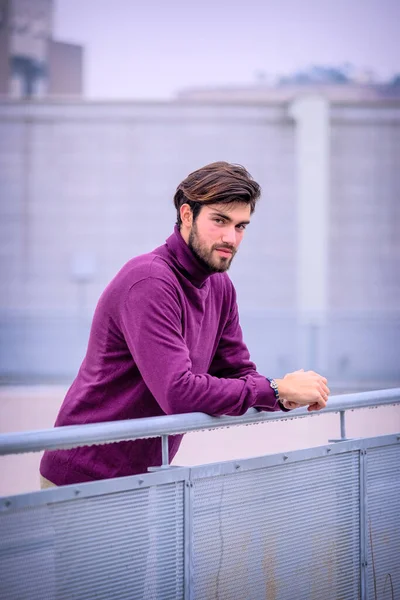 Terasta metal korkuluklara yaslanmış yakışıklı siyah saçlı çocuk. Yüksek kalite fotoğraf