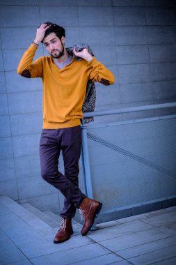 Yakışıklı, siyah saçlı, metal korkuluklara yaslanmış bir çocuk. Yüksek kalite fotoğraf