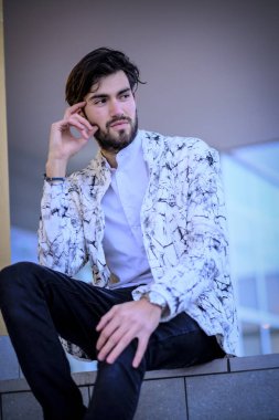 Beyaz merdivenlerde oturan yakışıklı, siyah saçlı İtalyan adam. Yüksek kalite fotoğraf