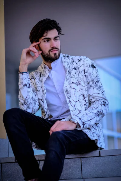 Beyaz merdivenlerde oturan yakışıklı, siyah saçlı İtalyan adam. Yüksek kalite fotoğraf