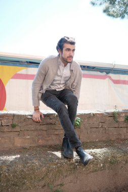 Yakışıklı, siyah saçlı, siyah çocuk tuğla duvarda oturuyor. Yüksek kalite fotoğraf