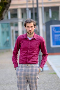 Şehir merkezinde koyu kırmızı tişörtlü yakışıklı, koyu renk saçlı İtalyan adam. Yüksek kalite fotoğraf