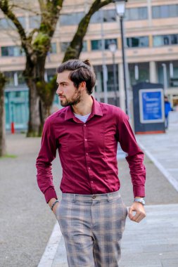 Şehir merkezinde koyu kırmızı tişörtlü yakışıklı, koyu renk saçlı İtalyan adam. Yüksek kalite fotoğraf