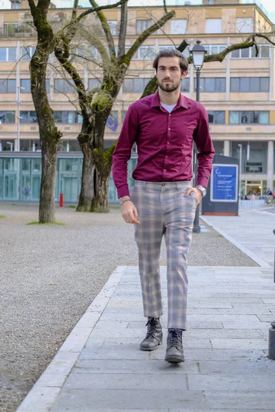 Şehir merkezinde koyu kırmızı tişörtlü yakışıklı, koyu renk saçlı İtalyan adam. Yüksek kalite fotoğraf