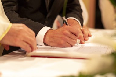 Damadın elleri Hıristiyan töreninde evlilik sözleşmesini imzalar. Yüksek kalite fotoğraf