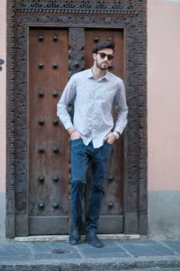 Yakışıklı İtalyan adam eski bir kapının önünde tişörtle poz veriyor. Yüksek kalite fotoğraf