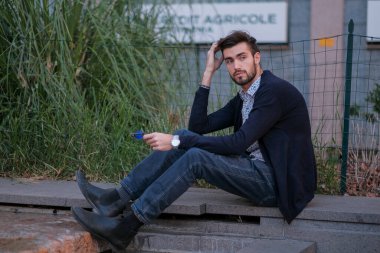 Parma 'daki antik merdivenlerde oturan yakışıklı İtalyan çocuk. Yüksek kalite fotoğraf