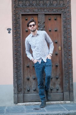 Yakışıklı İtalyan adam eski bir kapının önünde tişörtle poz veriyor. Yüksek kalite fotoğraf