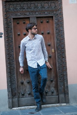 Yakışıklı İtalyan adam eski bir kapının önünde tişörtle poz veriyor. Yüksek kalite fotoğraf