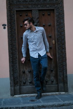 Yakışıklı İtalyan adam eski bir kapının önünde tişörtle poz veriyor. Yüksek kalite fotoğraf