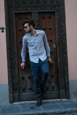 Yakışıklı İtalyan adam eski bir kapının önünde tişörtle poz veriyor. Yüksek kalite fotoğraf