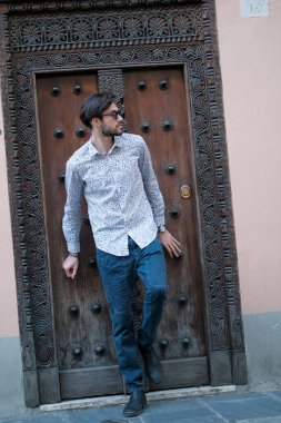 Yakışıklı İtalyan adam eski bir kapının önünde tişörtle poz veriyor. Yüksek kalite fotoğraf