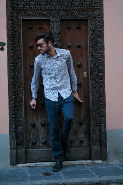 Yakışıklı İtalyan adam eski bir kapının önünde tişörtle poz veriyor. Yüksek kalite fotoğraf