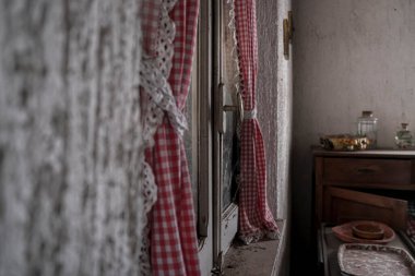 Terk edilmiş büyük bir evde kırmızı perdeli bir pencere. Yüksek kalite fotoğraf