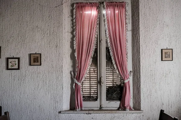 Terk edilmiş büyük bir evde kırmızı perdeli bir pencere. Yüksek kalite fotoğraf