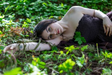 Kahverengi elbiseli, cansız vücutlu esmer kız sarmaşık çayırında yatıyor. Yüksek kalite fotoğraf