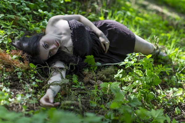 Kahverengi elbiseli, cansız vücutlu esmer kız sarmaşık çayırında yatıyor. Yüksek kalite fotoğraf