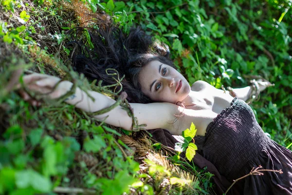 Kahverengi elbiseli, cansız vücutlu esmer kız sarmaşık çayırında yatıyor. Yüksek kalite fotoğraf