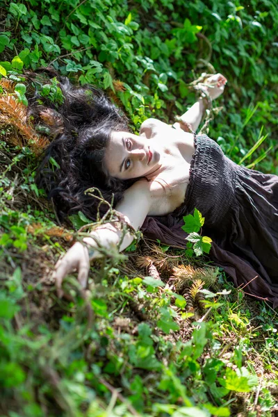 Kahverengi elbiseli, cansız vücutlu esmer kız sarmaşık çayırında yatıyor. Yüksek kalite fotoğraf