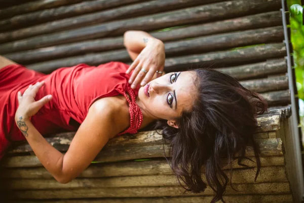長い赤いドレスを着た美しい女の子がベンチに横たわっていた 高品質の写真 — ストック写真