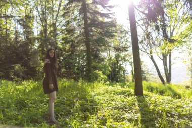 Kısa kahverengi elbiseli güzel İtalyan kız ormanda yalınayak yürüyor. Yüksek kalite fotoğraf