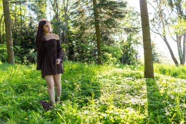 Kısa kahverengi elbiseli güzel İtalyan kız ormanda yalınayak yürüyor. Yüksek kalite fotoğraf