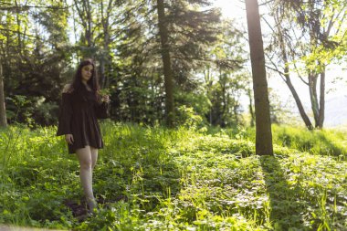 Kısa kahverengi elbiseli güzel İtalyan kız ormanda yalınayak yürüyor. Yüksek kalite fotoğraf