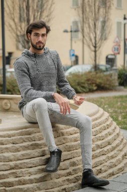 Yakışıklı, siyah saçlı İtalyan çocuk anıtın üzerinde oturuyor. Yüksek kalite fotoğraf