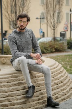 Yakışıklı, siyah saçlı İtalyan çocuk anıtın üzerinde oturuyor. Yüksek kalite fotoğraf