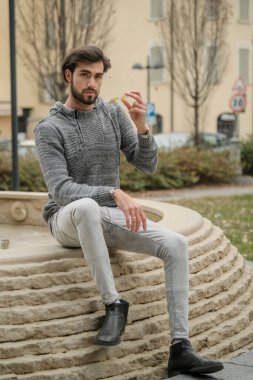 Yakışıklı, siyah saçlı İtalyan çocuk anıtın üzerinde oturuyor. Yüksek kalite fotoğraf