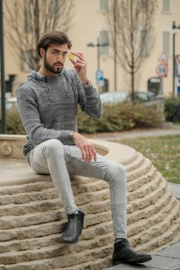 Yakışıklı, siyah saçlı İtalyan çocuk anıtın üzerinde oturuyor. Yüksek kalite fotoğraf