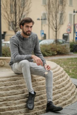 Yakışıklı, siyah saçlı İtalyan çocuk anıtın üzerinde oturuyor. Yüksek kalite fotoğraf