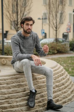 Yakışıklı, siyah saçlı İtalyan çocuk anıtın üzerinde oturuyor. Yüksek kalite fotoğraf