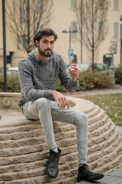 Yakışıklı, siyah saçlı İtalyan çocuk anıtın üzerinde oturuyor. Yüksek kalite fotoğraf