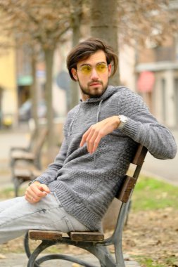 Bankta oturan koyu renk tişörtlü yakışıklı İtalyan çocuk. Yüksek kalite fotoğraf