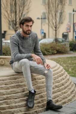 Yakışıklı, siyah saçlı İtalyan çocuk anıtın üzerinde oturuyor. Yüksek kalite fotoğraf