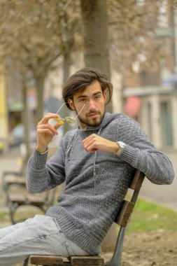 Bankta oturan koyu renk tişörtlü yakışıklı İtalyan çocuk. Yüksek kalite fotoğraf