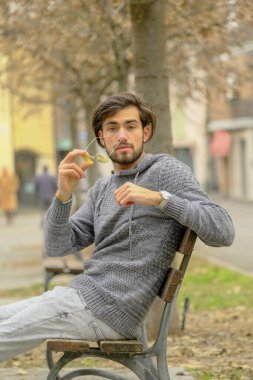 Bankta oturan koyu renk tişörtlü yakışıklı İtalyan çocuk. Yüksek kalite fotoğraf