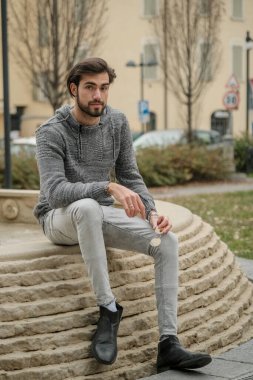 Yakışıklı, siyah saçlı İtalyan çocuk anıtın üzerinde oturuyor. Yüksek kalite fotoğraf