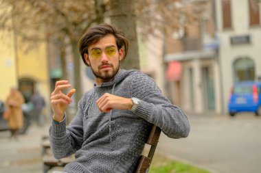 Bankta oturan koyu renk tişörtlü yakışıklı İtalyan çocuk. Yüksek kalite fotoğraf