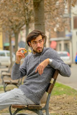 Bankta oturan koyu renk tişörtlü yakışıklı İtalyan çocuk. Yüksek kalite fotoğraf