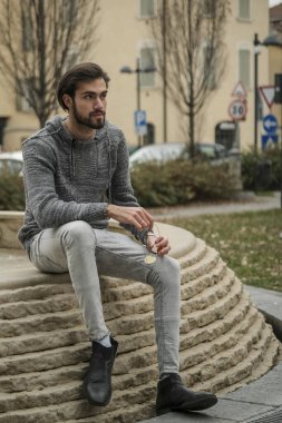 Yakışıklı, siyah saçlı İtalyan çocuk anıtın üzerinde oturuyor. Yüksek kalite fotoğraf