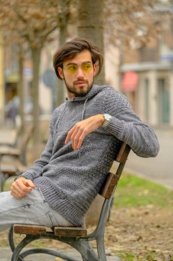 Bankta oturan koyu renk tişörtlü yakışıklı İtalyan çocuk. Yüksek kalite fotoğraf