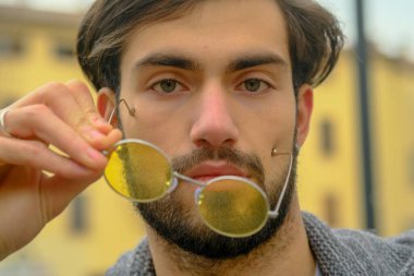 Sarı gözlüklü yakışıklı, koyu renk saçlı bir İtalyan portresi. Yüksek kalite fotoğraf