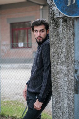 Duvara dayanmış yakışıklı, siyah saçlı bir İtalyan portresi. Yüksek kalite fotoğraf